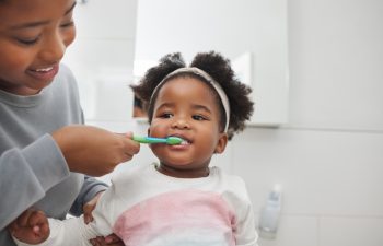 Mom will help her keep her baby teeth clean. Shot of a mother brushing her little daughters teeth in the bathroom at home.
