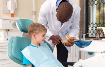 african dentist explaining the dental procedure to little boy